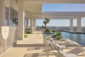 A rooftop pool area with lounge chairs and a view of the city.