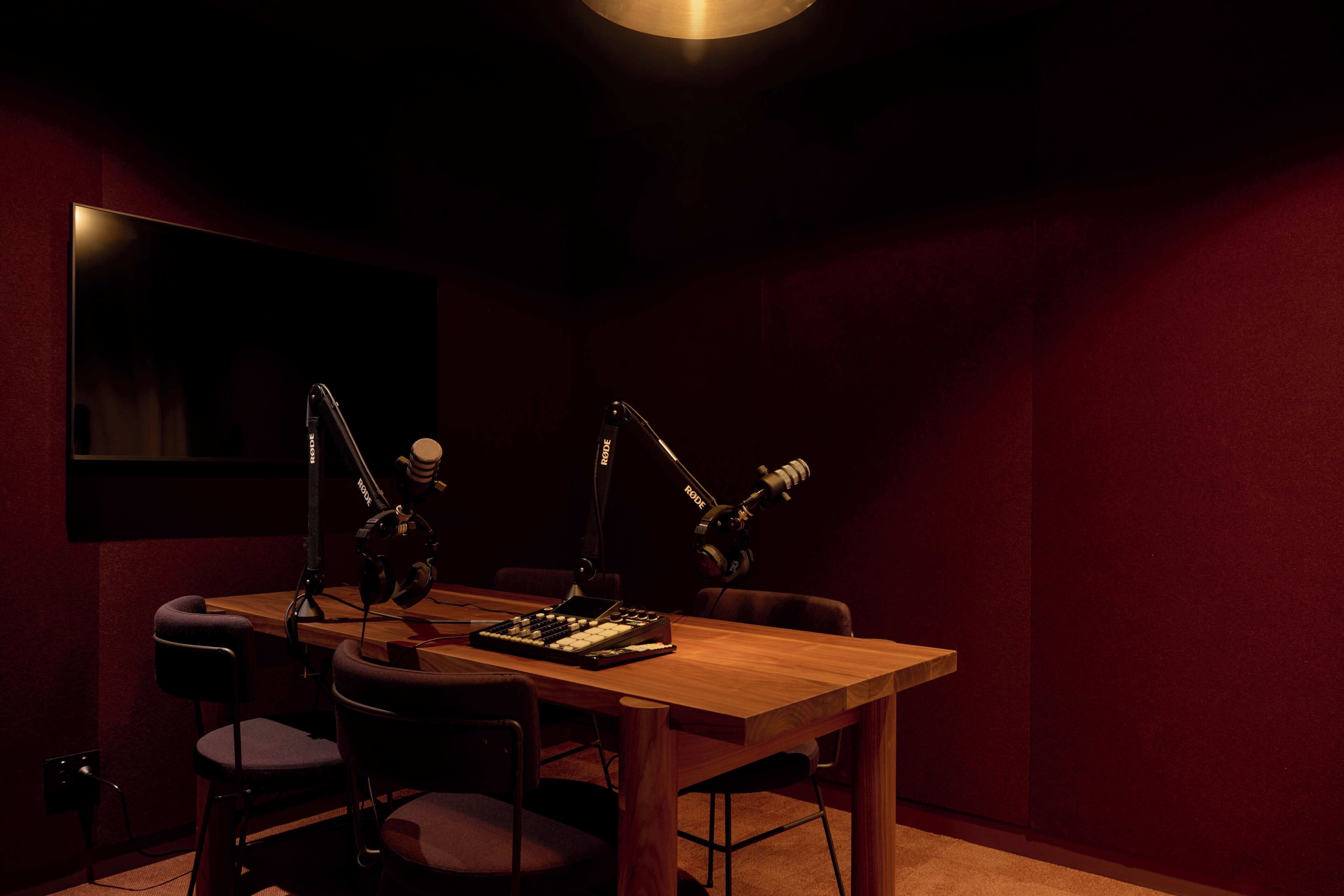 A recording studio with a wooden table, two chairs, and two microphones.