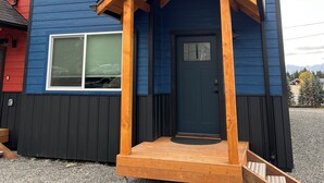 A two-story house with a blue exterior and a wooden front porch. - Heart of Homer - Redoubt (Homer)
