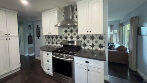 A modern kitchen with white cabinets, a stainless steel range hood, and a patterned backsplash. - Vintage Charm, Modern Comfort & Private Casita. Near Downtown Prescott. (Prescott)