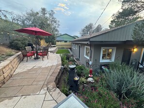 Eine Terrasse mit Gartenmöbeln, einer Feuerstelle und einem Garten mit verschiedenen Pflanzen und Blumen.