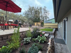 Eine Terrasse mit Gartenmöbeln, einem Grill und einem Gartenbereich mit verschiedenen Pflanzen.