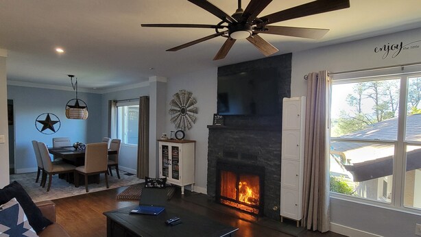 A living room with a fireplace, a ceiling fan, and a dining area with a star wall decoration. - Vintage Charm, Modern Comfort & Private Casita. Near Downtown Prescott. (Prescott)
