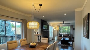 A modern dining area with a wooden table and chairs, a decorative hanging light, and a fireplace in the background. - Vintage Charm, Modern Comfort & Private Casita. Near Downtown Prescott. (Prescott)