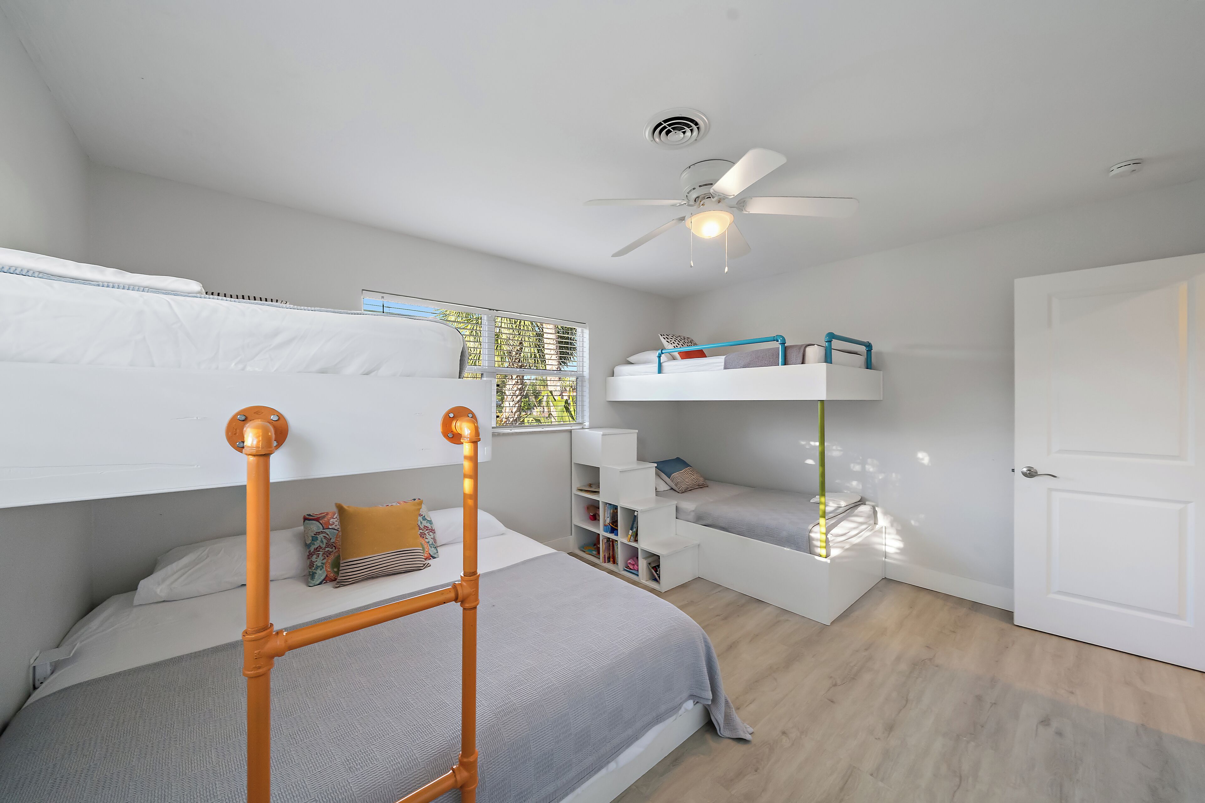 A bedroom with bunk beds, a ceiling fan, and built-in shelving.