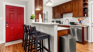 Una cocina moderna con armarios de madera, una puerta roja y una zona de bar con taburetes.