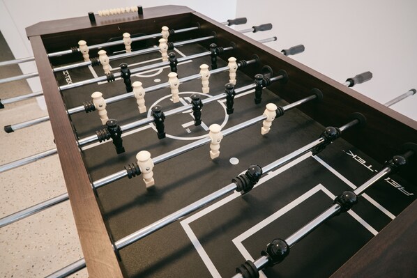 Una mesa de futbolín con estructura de madera oscura y barras de metal.