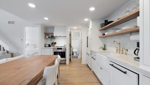 A modern kitchen with white cabinetry, wooden countertops, and a central island.