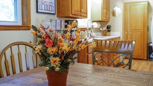 A dining table with a potted plant in the center, wooden chairs, and wooden cabinets in the background. - Lookout Mtn. Escape w/ Fire Pit & 1 Acre Level Lawn- Mins to Cloudland Canyon (Rising Fawn)