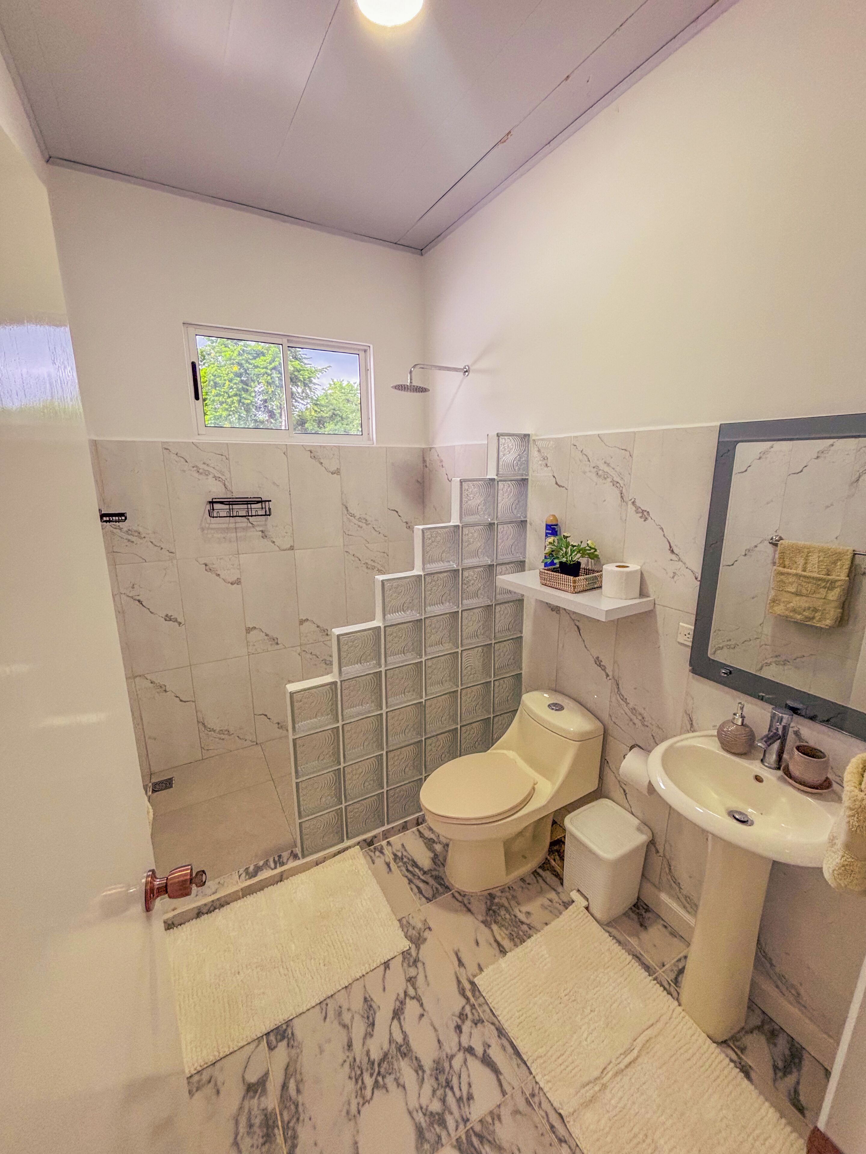 Et badeværelse med toilet, håndvask og bruseområde.