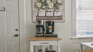 A kitchen area with a coffee maker, a tea station, and a decorative wall piece. - Cozy 2nd-Floor Suite near Beach, The Strand, Pier (Galveston)