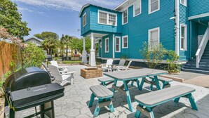 A backyard with a barbecue grill, outdoor seating, and a blue house. - 3 Room 2nd-Floor Suite near Beach, Pier, Strand (Galveston)