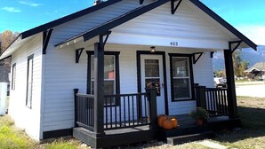 Una casa blanca pequeña con detalles negros y un porche, número 403.