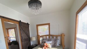 Una cama con estructura de madera, cabecera, lámpara de noche y un osito de peluche sobre la cama.