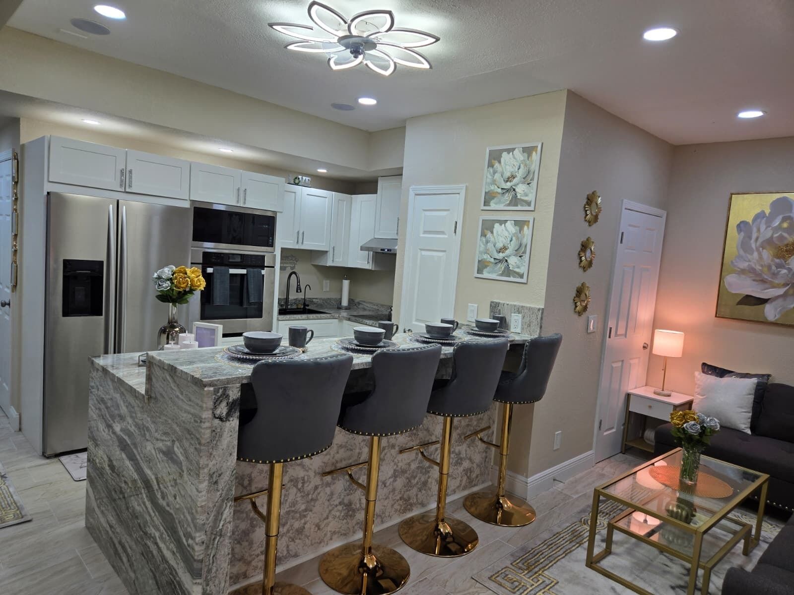 A modern kitchen with a central island, bar stools, and a dining area with a sofa and coffee table.