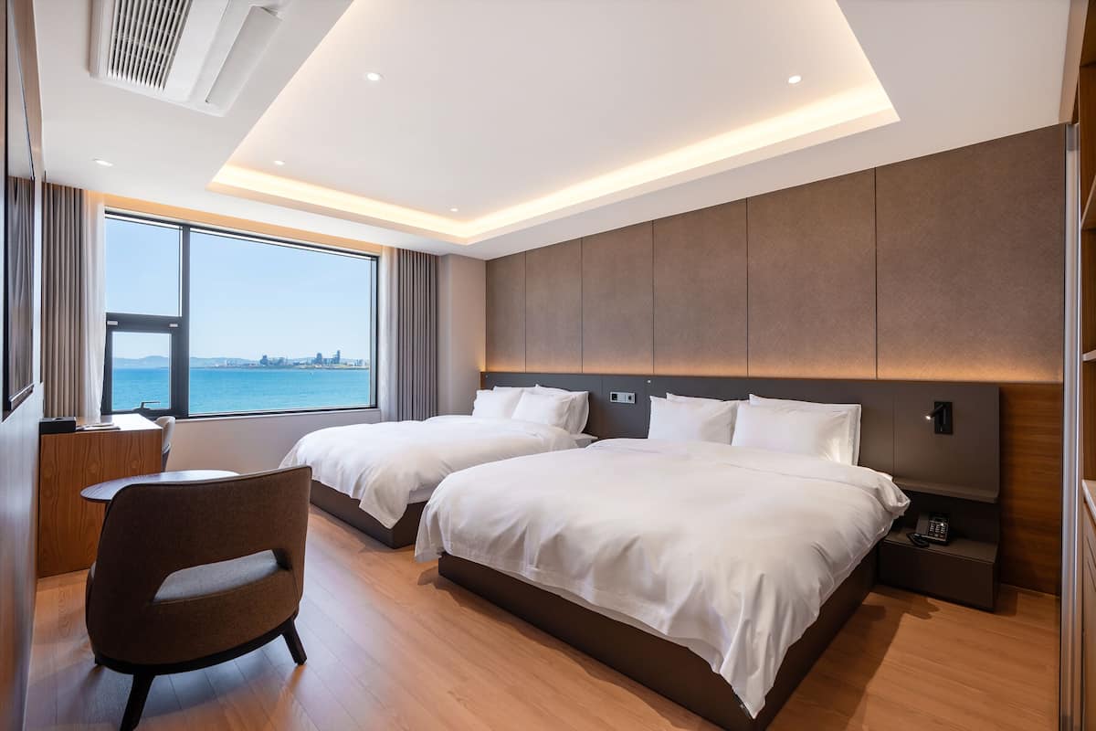 Une chambre d’hôtel moderne avec deux lits, un bureau et une vue sur la mer.