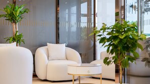 Una sala de estar moderna con un sofá blanco, una mesa de centro redonda y plantas en macetas.