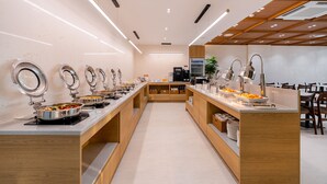 Un moderno montaje tipo bufé con varias estaciones de servicio, una máquina de café y una zona de estar con sillas.