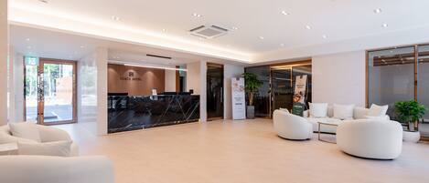 A modern hotel lobby with a reception desk, seating area, and a view of the reception area.