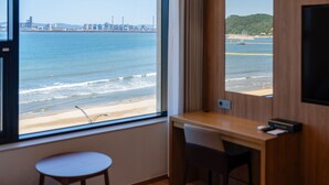 Habitación de hotel con un ventanal amplio que ofrece vista a la playa y al océano.