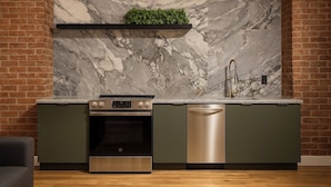 A kitchen with a marble backsplash, a built-in oven, a dishwasher, and a stainless steel faucet.