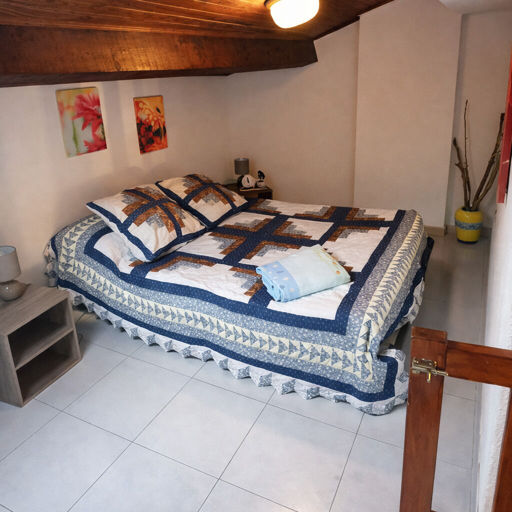 Un dormitorio con una cama grande, una mesita de noche, una lámpara y un estante pequeño.