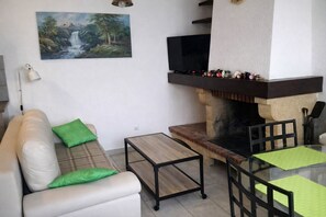 A living room with a sofa, a coffee table, a fireplace, a TV, and a painting on the wall. - Cosy village house (Aragon)