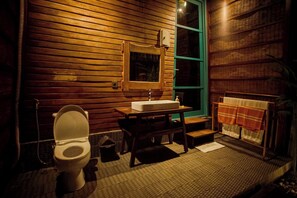 A bathroom with a wooden interior, a sink, a mirror, and a towel rack. - Waras Villa (Gili Trawangan)