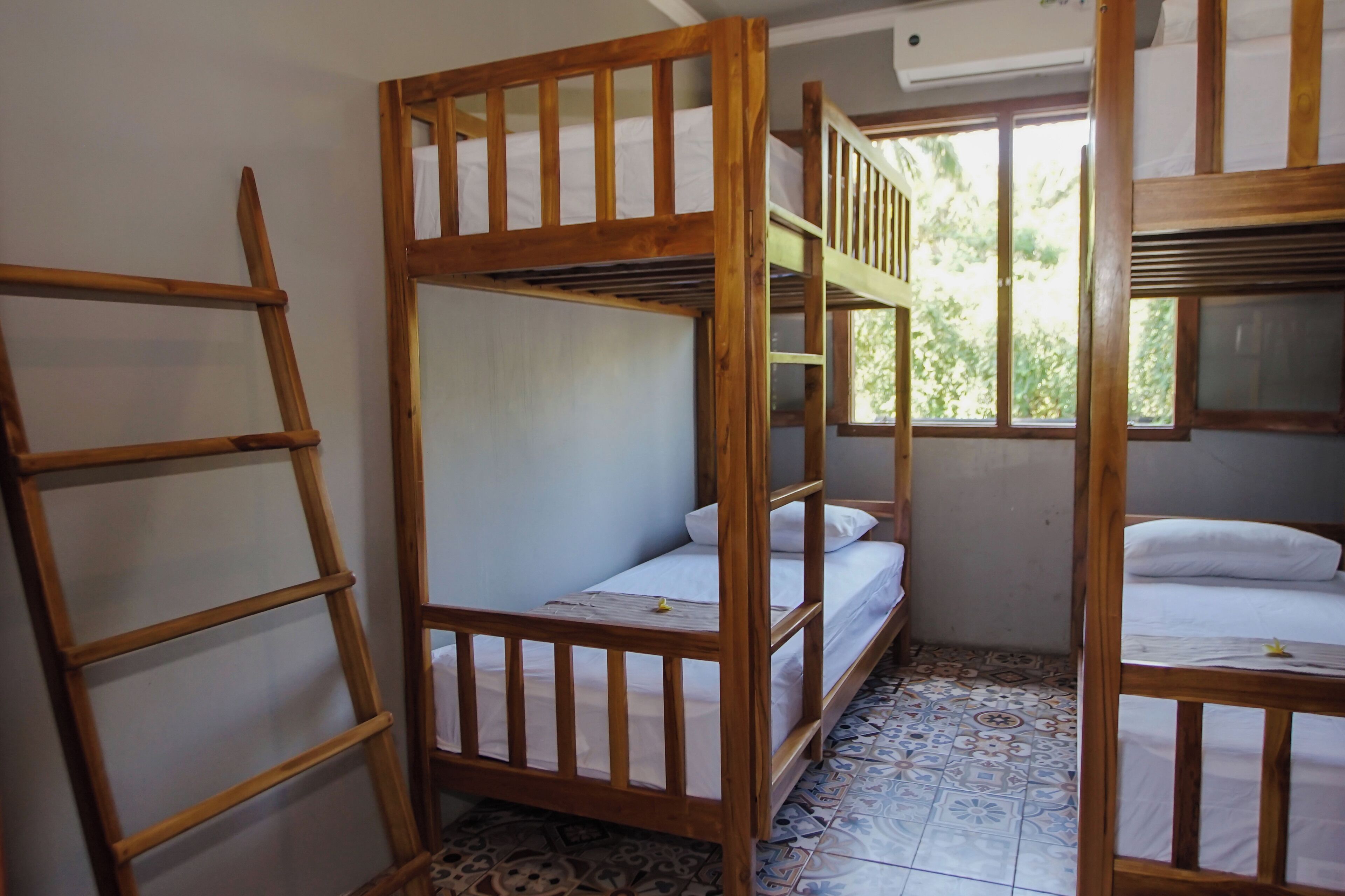 A dormitory room with bunk beds, a ladder, and a tiled floor.