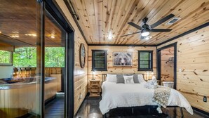 Ein Schlafzimmer in einer Holzhütte mit einem Bett, einem Nachttisch, einer Wanduhr und einem gerahmten Bild.