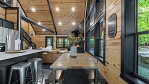 Eine moderne Küche mit Holzwänden, einem Essbereich mit Tisch und Stühlen und Blick ins Freie.