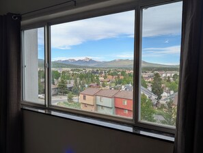 Een uitzicht op een stad en bergen vanuit een raam.
