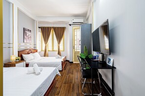 A hotel room with two beds, a desk, a TV, and a large window with curtains. - Saigon Central Group Stay  (Ho Chi Minh City)