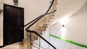 A staircase with a black door labeled P.101, a curved railing, and a wall-mounted light fixture. - Saigon Central Group Stay  (Ho Chi Minh City)