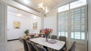 A modern dining area with a marble table, grey upholstered chairs, and a vase of flowers. - Saigon Central Group Stay  (Ho Chi Minh City)