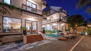 A multi-story hotel with a pool area, outdoor seating, and a staircase leading to the entrance. - CocoPalm Hoi An River Beach By JM Villas (Hoi An)