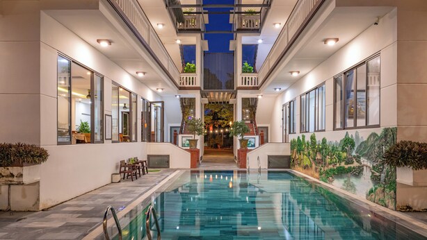 A pool area with a central water feature, surrounded by seating and potted plants. - CocoPalm Hoi An River Beach By JM Villas (Hoi An)