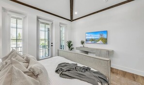 A bedroom with a bed, a nightstand, a painting, and a window with blinds. - New Canal Front Beach House on AMI! Gorgeous Pool! (Anna Maria)