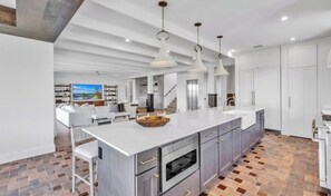 A modern kitchen with a large island, stainless steel appliances, and pendant lighting. - New Canal Front Beach House on AMI! Gorgeous Pool! (Anna Maria)