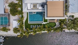 A residential property with a swimming pool, a wooden deck, and a fenced garden area. - New Canal Front Beach House on AMI! Gorgeous Pool! (Anna Maria)