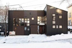 A modern two-story building with a dark exterior, large windows, and a flat roof.