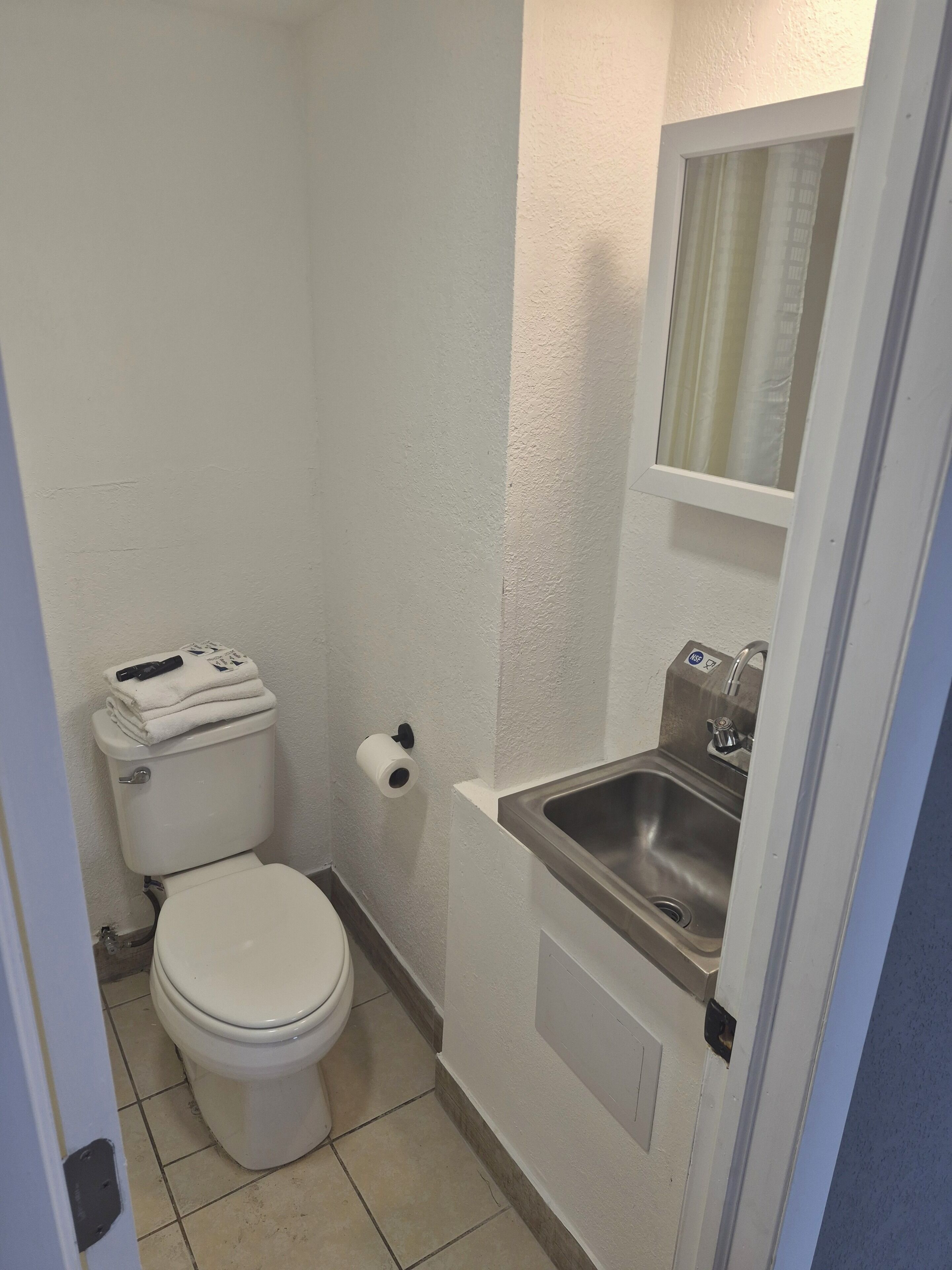 Une petite salle de bain comprenant des toilettes, un lavabo et un porte-rouleau de papier toilette.