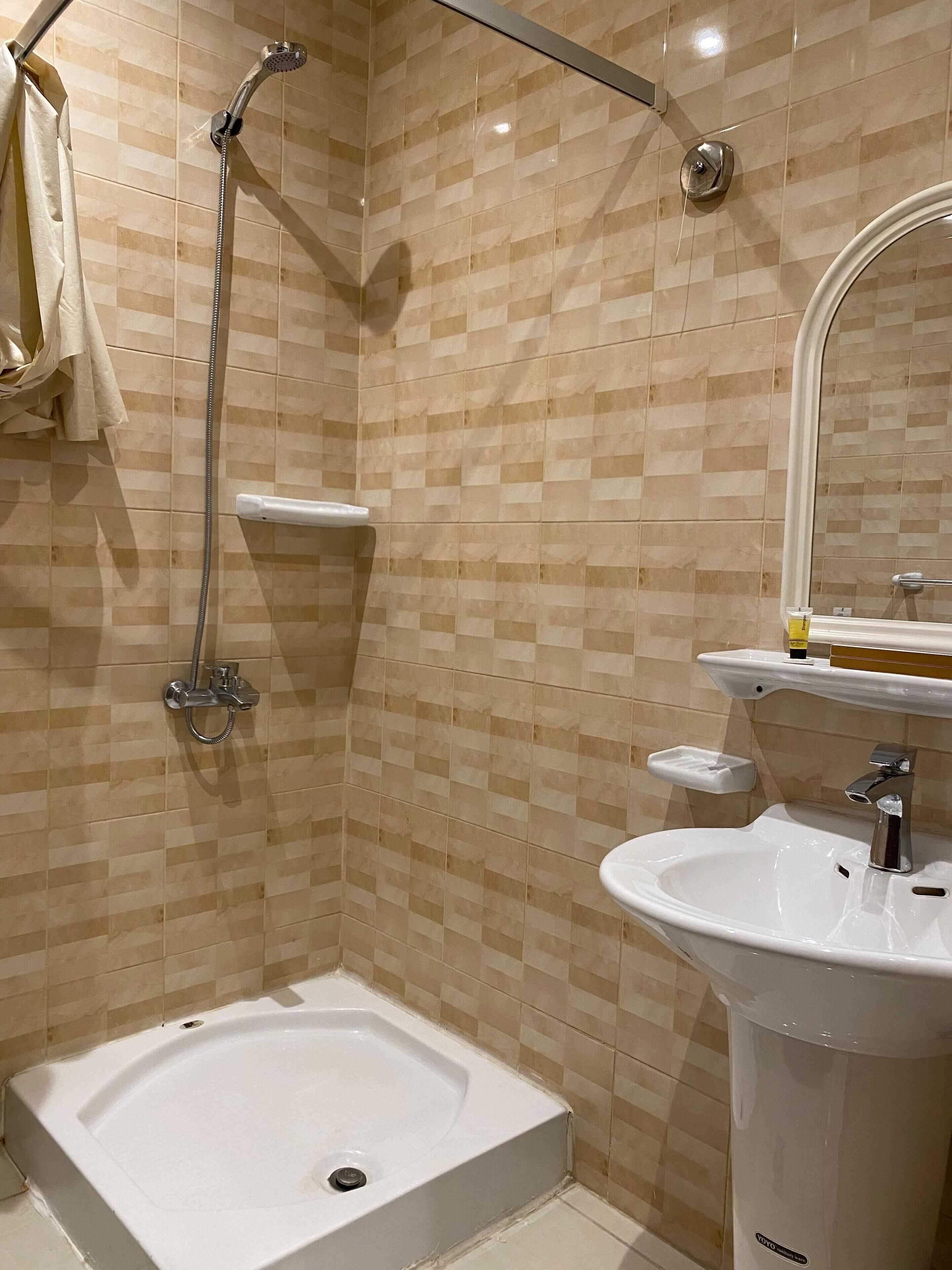 Un baño con ducha, lavamanos y espejo.