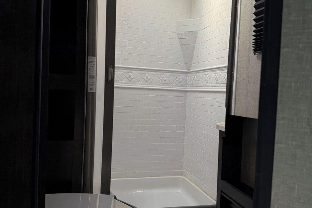 Ein Eckbereich eines Raumes mit weiß gefliesten Wänden und einer weißen Badewanne.