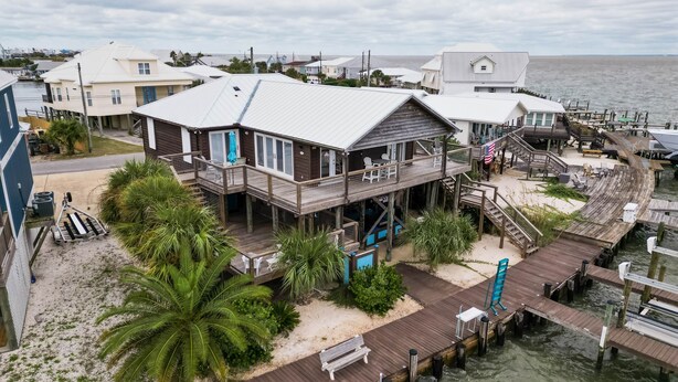 A coastal house with a wooden deck, a small porch, and a view of the water.