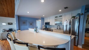 A modern kitchen with a large island, white cabinetry, stainless steel appliances, and a blue accent wall.