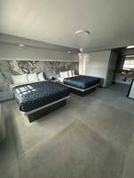 Una habitación de hotel moderna con dos camas, cabecera de mármol y un ventanal grande.