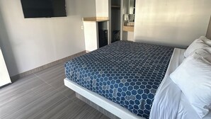 A modern hotel room with a large bed, a flat-screen TV mounted on the wall, and a walk-in closet. - Hometown Inn (Los Banos)