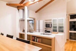 A compact kitchen with a dining table, white cabinets, and a microwave.