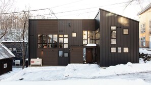 A modern two-story building with large windows and a garage door. - Casi67 West | 2BR Hirafu Chalet | Yotei & Annupuri Views (Kutchan)